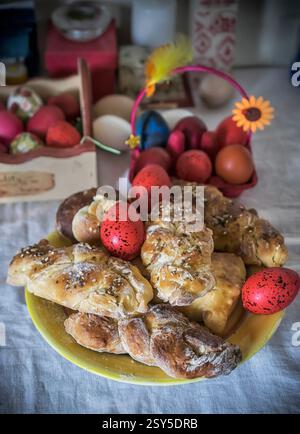 Sweet Easter buns on a plate and decorated eggs on a festive table Stock Photo