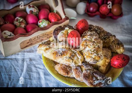 Sweet Easter buns on a plate and decorated eggs on a festive table Stock Photo