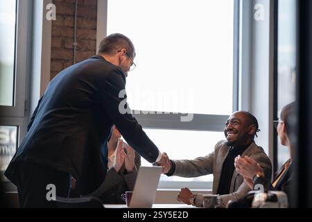 Business professionals shaking hands in a modern office during a meeting. Concept of partnership, agreement, teamwork, corporate success, diversity Stock Photo