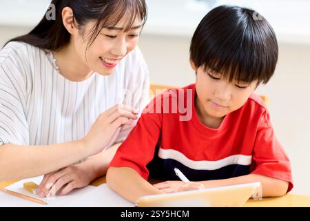 Japanese Mother And Son Doing Homework At Home Stock Photo