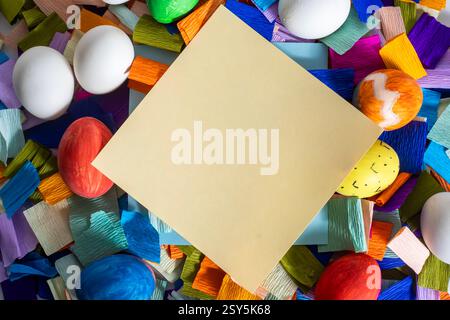 A blank yellow notebook surrounded by colorful eggs and vibrant pieces of paper for Easter celebration. Stock Photo