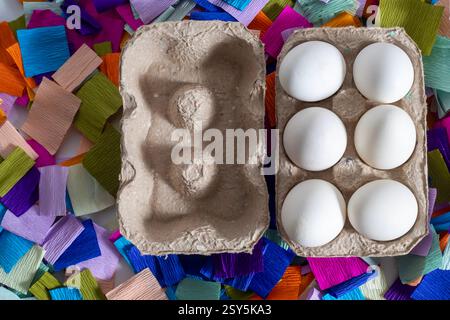 Top view of white eggs placed in a cardboard box on a colorful paper background. Stock Photo