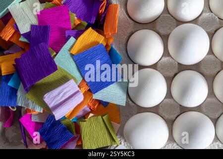 Top view of white eggs placed in a cardboard box on a colorful paper background. Stock Photo