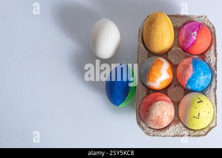Hand-painted Easter eggs with vibrant patterns and designs arranged in a cardboard box on a white surface. Stock Photo