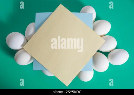 Happy Easter. A blank sheet of paper placed on top of a white egg placed on a vibrant green background. Stock Photo