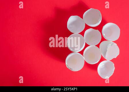 Top view of white eggshells are grouped together on a vibrant red background, emphasizing color contrast and texture. Stock Photo