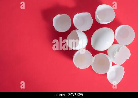 Top view of white eggshells are grouped together on a vibrant red background, emphasizing color contrast and texture. Stock Photo