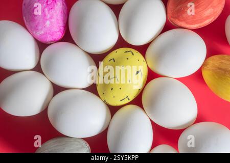 Top view of painted and plain white eggs displayed on a red background. Stock Photo