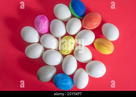 Top view of painted and plain white eggs displayed on a red background. Stock Photo