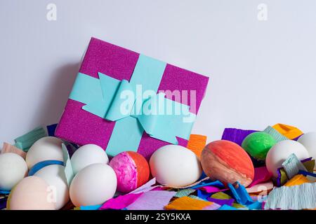 Easter greeting card, colorful Easter eggs with gift box and crepe paper on white background, with copy space. Stock Photo
