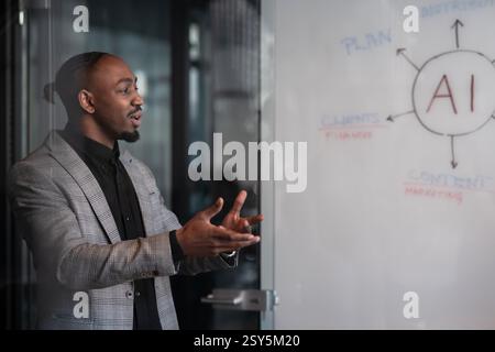 Professional African-American man in a plaid blazer gives a presentation in a modern office, gesturing while speaking. Concept of business Stock Photo