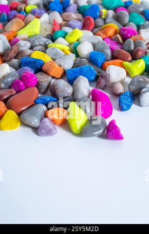 A collection of polished and colorful decorative stones arranged over a white surface, showcasing bright and vivid hues. Stock Photo