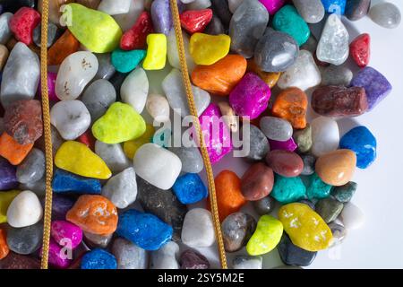 Top view of gold chain on top of vibrant colorful stones on a white surface Stock Photo
