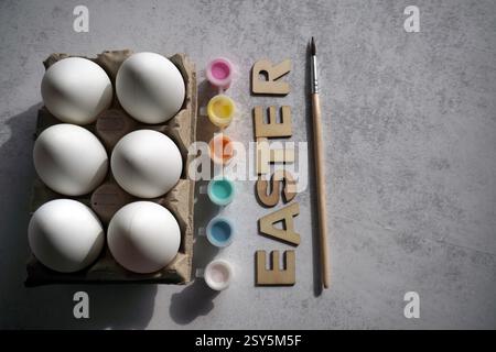 easter holidays DIY painting concept. Eggs, colorful paints, brush and white eggs in paper holder, box. White background, place for the copy Stock Photo