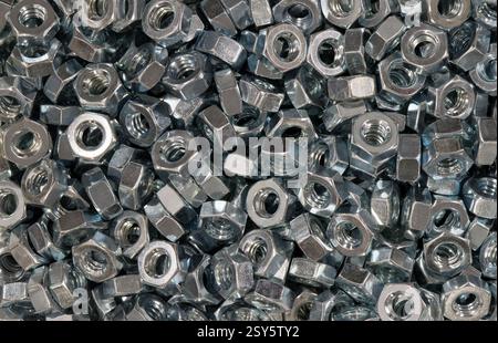 Metal nuts scattered loosely mechanical hardware fasteners machine parts work tools. Stock Photo