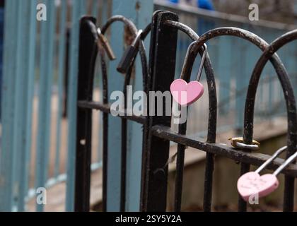 pink padlock in the shape of a heart locked on a fence. Stock Photo