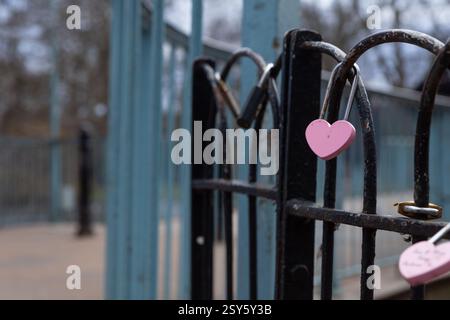pink padlock in the shape of a heart locked on a fence. Stock Photo