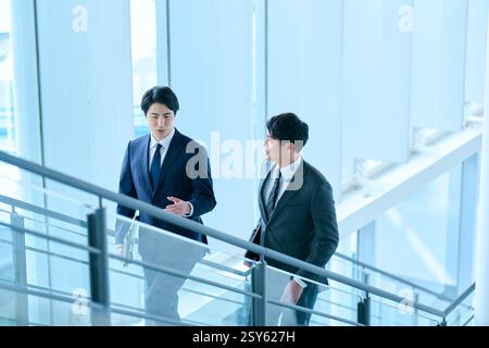 Two Japanese Businessmen Walking Up A Stairwell Stock Photo