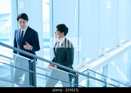 Two Japanese Businessmen Walking Up A Stairwell Stock Photo