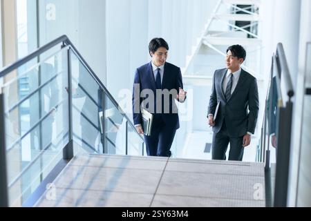 Two Japanese Businessmen Walking Up A Stairwell Stock Photo
