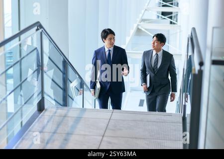 Two Japanese Businessmen Walking Up A Stairwell Stock Photo