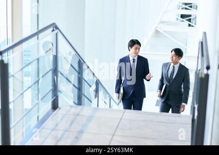 Two Businessmen In Suits Walking Up A Stairwell Stock Photo