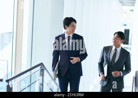 Two Japanese Businessmen Walking Up A Stairwell Stock Photo