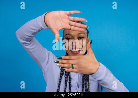 Happy young woman framing her face with hands, smiling and looking through the frame she created with her fingers Stock Photo