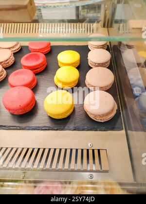 Traditional French multicolored macarons on display in a cafe, vertical Stock Photo
