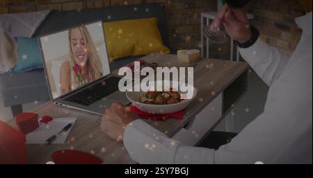 Image of hearts falling over caucasian man eating pasta having image call with caucasian woman Stock Photo