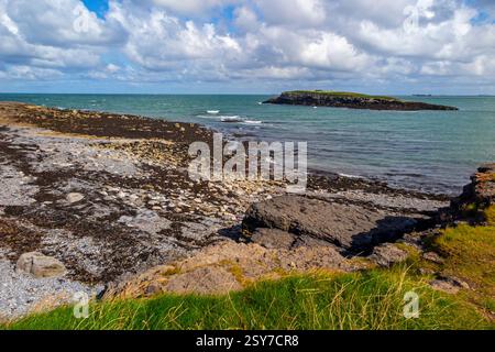 View looking from the beach across the channel Y Swnt towards Ynys Moelfre a small island off the coast of north east Anglesey in North Wales UK. Stock Photo