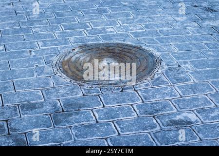 Manhole and interlock bricks with frost on them. Stock Photo