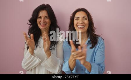 Women clapping joyfully in front of a pink wall, epitomizing love, friendship, family, and togetherness, featuring middle-aged sisters or friends, sho Stock Photo