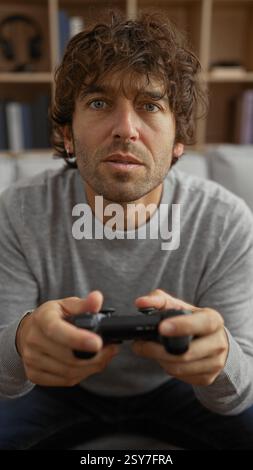Young man playing video games indoors, concentrating intently in a comfortable home setting. Stock Photo