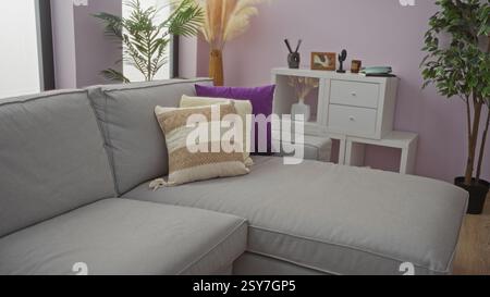 Cozy living room with modern sofa, decorative pillows, potted plants, and stylish decor creating a warm, inviting home atmosphere in a well-designed i Stock Photo