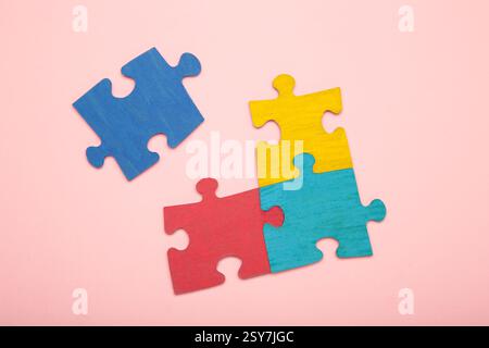 Colorful puzzle on pink background. Multi-colored heart as a symbol of World Autism Awareness Day. Stock Photo