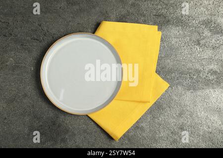 Yellow napkin and empty plate on grey table, top view Stock Photo
