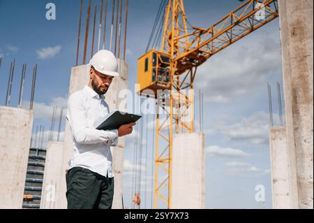 Inspector with notepad is standing on the construction site. Stock Photo