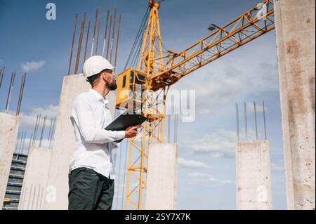 Inspector with notepad is standing on the construction site. Stock Photo