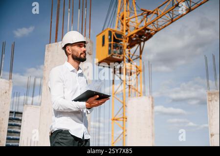 Inspector with notepad is standing on the construction site. Stock Photo
