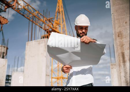 Inspecting a plan. Man in uniform is working on the construction site. Stock Photo