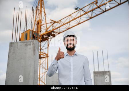 Smiling and showing thumb up. Man in uniform is working on the construction site. Stock Photo