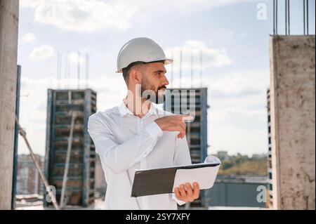 With notepad with documents. Foreman in uniform is working on the construction site. Stock Photo
