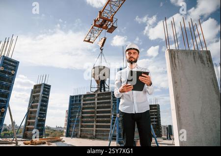 With notepad with documents. Foreman in uniform is working on the construction site. Stock Photo