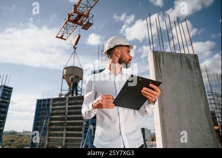 With notepad with documents. Foreman in uniform is working on the construction site. Stock Photo