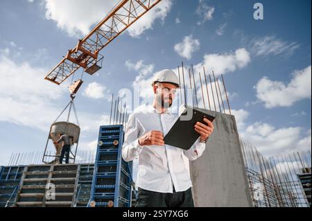 With notepad with documents. Foreman in uniform is working on the construction site. Stock Photo