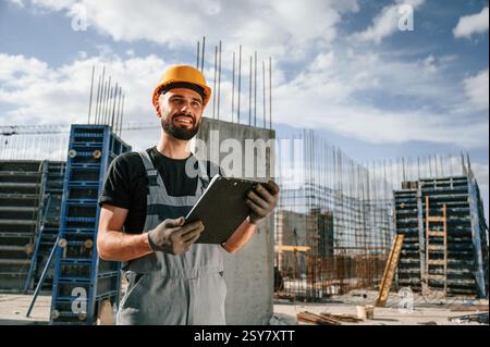 Control of the process. Foreman is with documents. Man in uniform is working on the construction site. Stock Photo