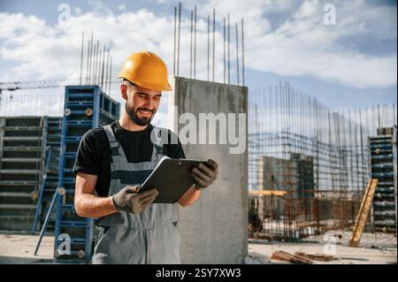Control of the process. Foreman is with documents. Man in uniform is working on the construction site. Stock Photo