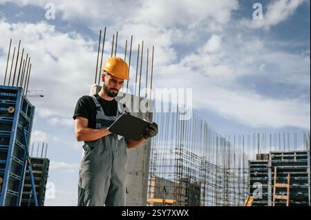 Control of the process. Foreman is with documents. Man in uniform is working on the construction site. Stock Photo