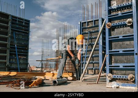Using the drill. Man in uniform is working on the construction site. Stock Photo